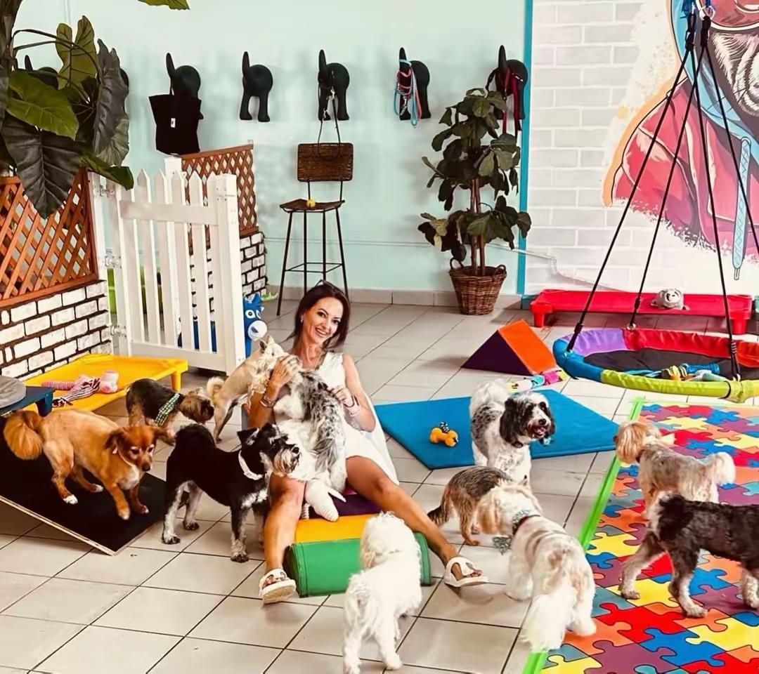 Dogtopia staff member surrounded by happy daycare dogs